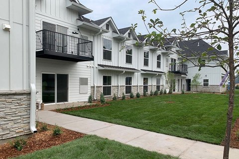 a group of white houses with a yard and sidewalk
