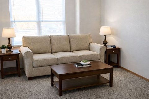 A beige couch sits in a living room with a coffee table in front of it.