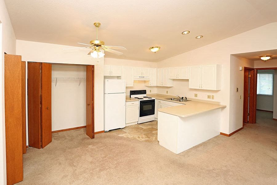an empty kitchen with a white counter top