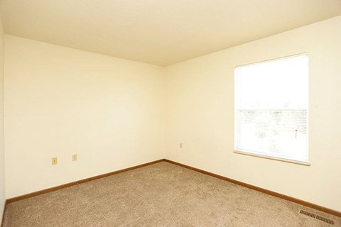 an empty room with a window and a carpet