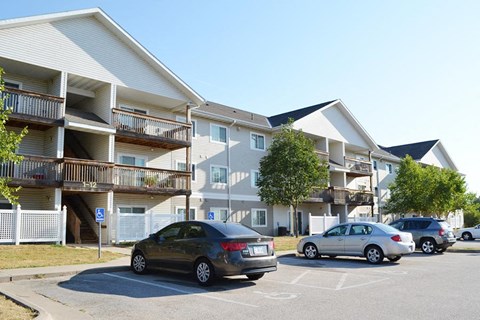 an apartment building with cars parked in a parking lot