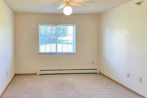 an empty living room with a ceiling fan and a window