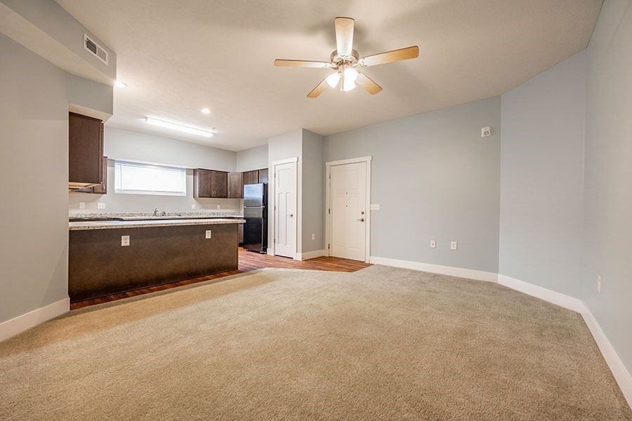 A spacious room with a ceiling fan and carpeted floor.