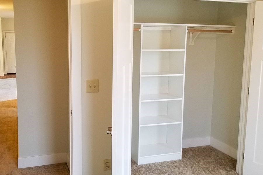 A white shelving unit in a room with a white door.