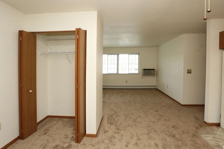 an empty living room with an open door to a closet