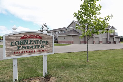 a sign for cobblestone estates apartments in front of a house
