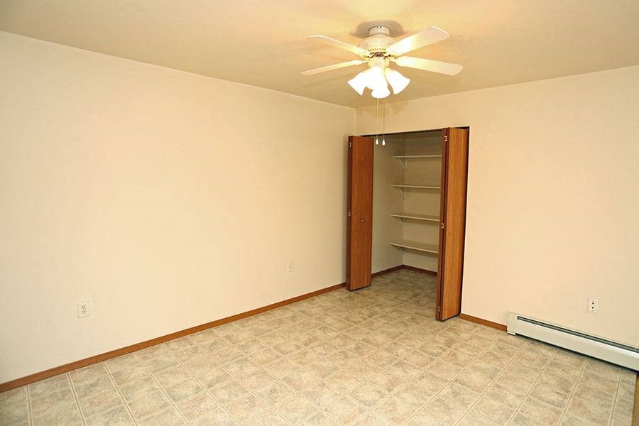 a empty room with a ceiling fan and a closet