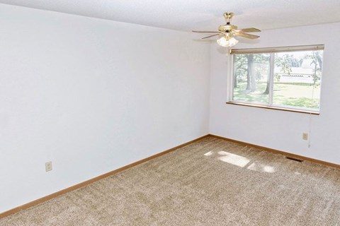 an empty room with a ceiling fan and a window