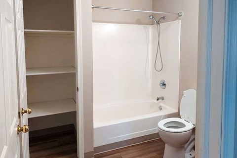 A white bathroom with a toilet, bathtub, and a cabinet.