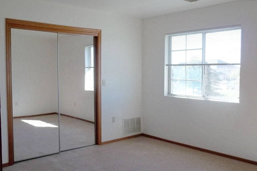 an empty bedroom with a mirror and a window