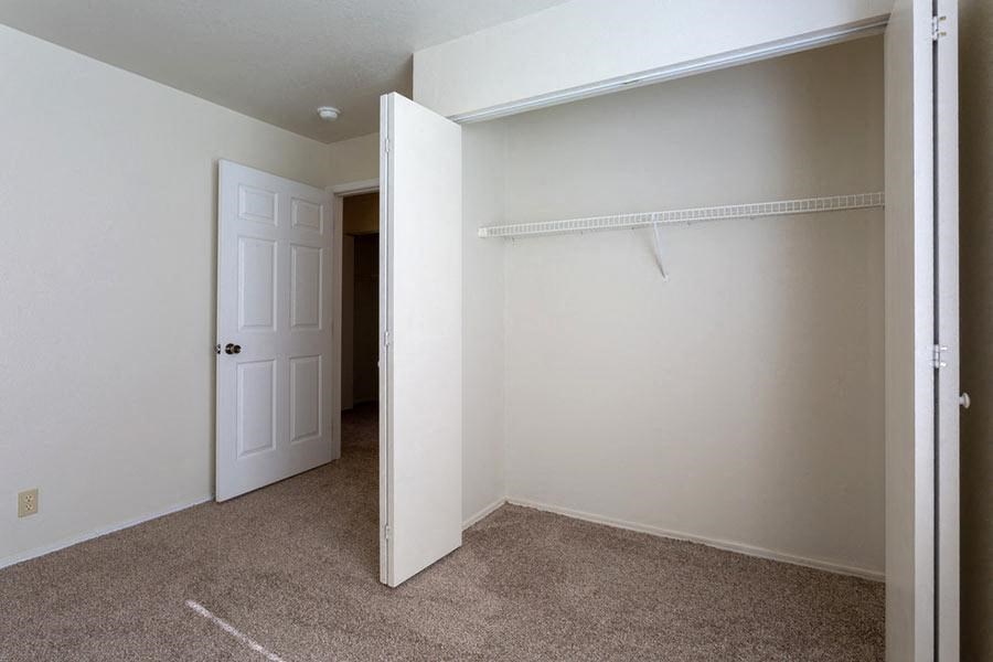 an empty bedroom with a closet and a white door