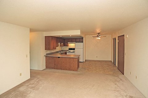 an empty living room and kitchen with a ceiling fan