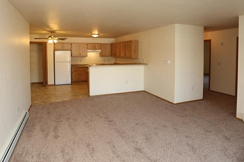 an empty living room and kitchen with a white refrigerator