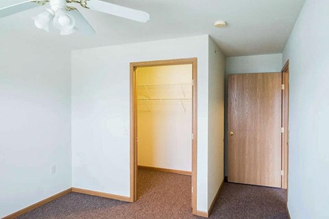 A room with a ceiling fan and a doorway leading to another room.