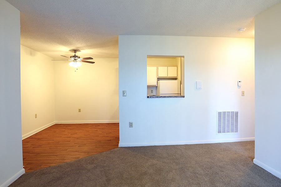 an empty living room with a ceiling fan