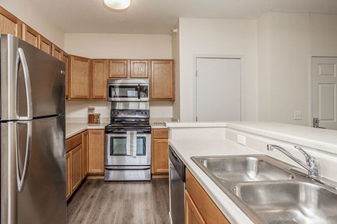 A kitchen with a stainless steel refrigerator, microwave, oven, and sink.