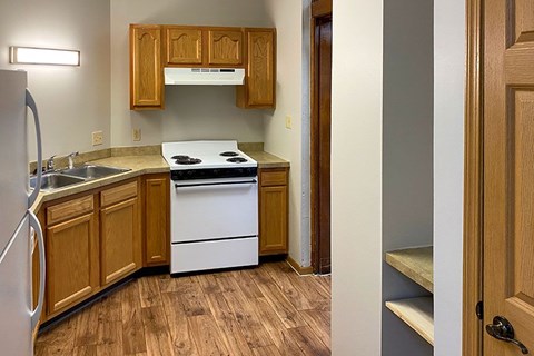 A kitchen with wooden cabinets and a white stove top oven.