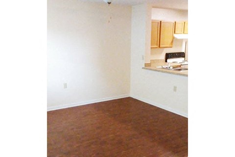 an empty living room and a kitchen with wood floors