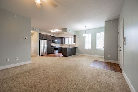A spacious living room with a kitchen in the background.