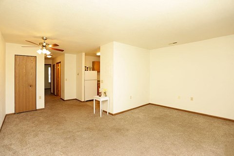 an empty living room with a ceiling fan