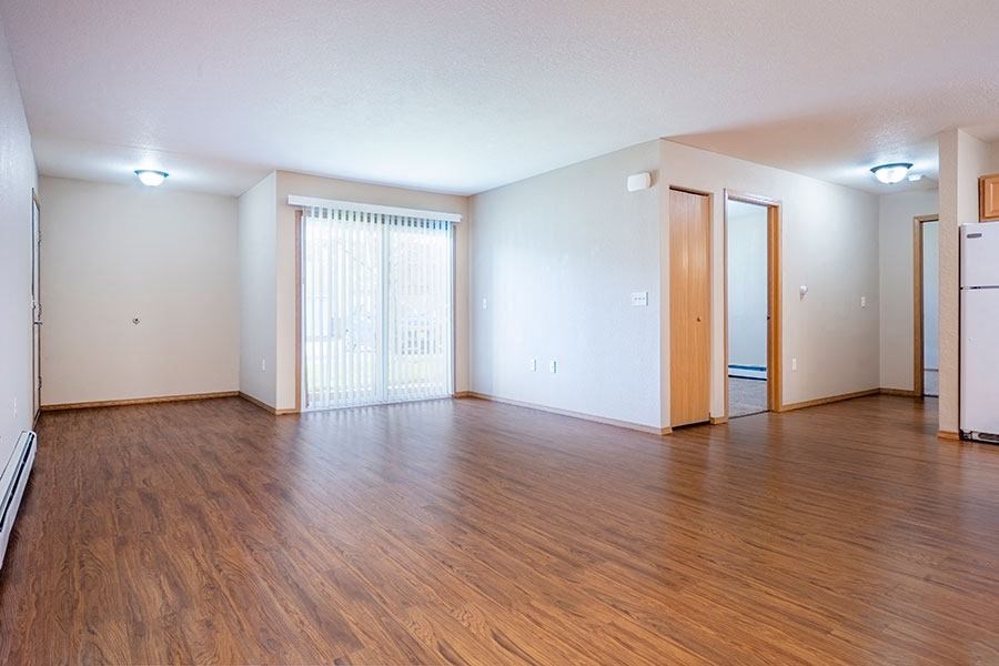 an empty living room with wood flooring and white walls