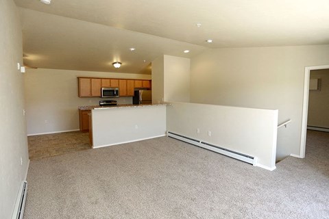an empty living room and kitchen with a white wall