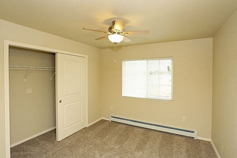 an empty bedroom with a ceiling fan and a closet