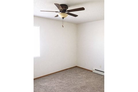 A room with a ceiling fan and carpeted floor.