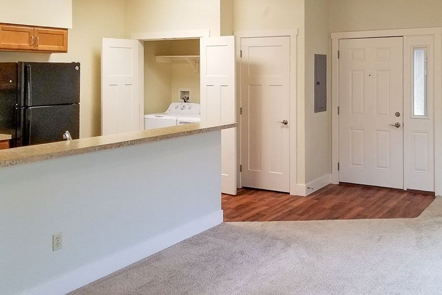 A kitchen area with a black fridge and white cabinets.