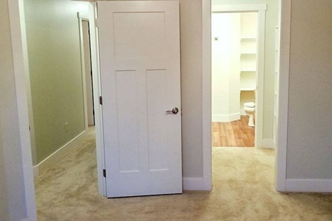 A white door is in a hallway with a carpeted floor.