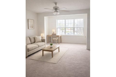 A living room with a white sofa, a wooden coffee table, and a ceiling fan.