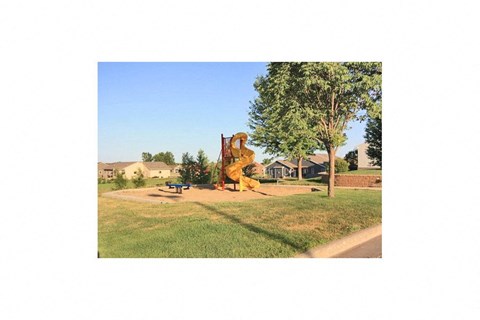 A playground with a slide and a tree in the foreground.