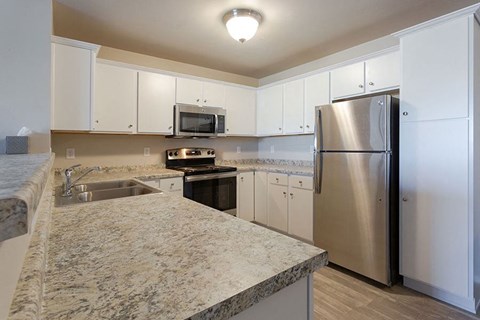 A kitchen with a granite counter top and stainless steel appliances.