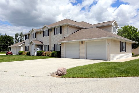 A house with a grey roof and a driveway with a rock in it.