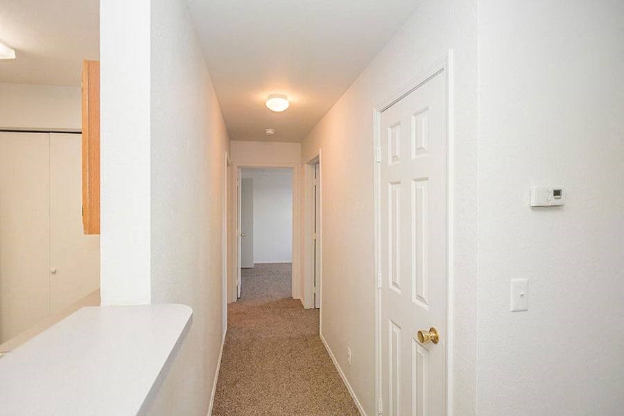 A long hallway with a white door at the end.