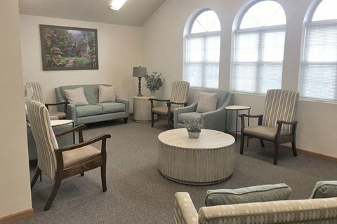 A living room with a large painting on the wall and a variety of seating options.