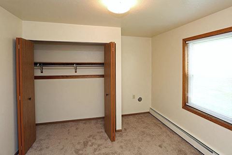 an empty bedroom with a closet and a window