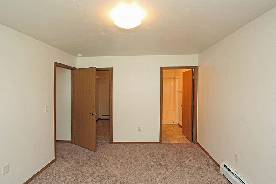 an empty living room with a door to a bedroom