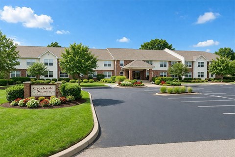 The image shows a beautiful day at the Creekside Seniors apartment complex.