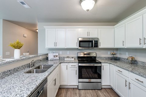 A modern kitchen with white cabinets and granite countertops.