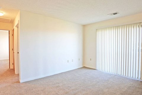 an empty living room with a large window and blinds