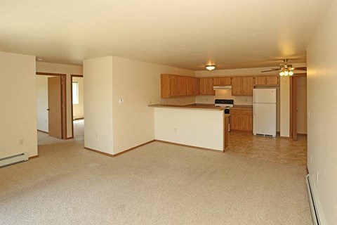 an empty living room and kitchen with a refrigerator