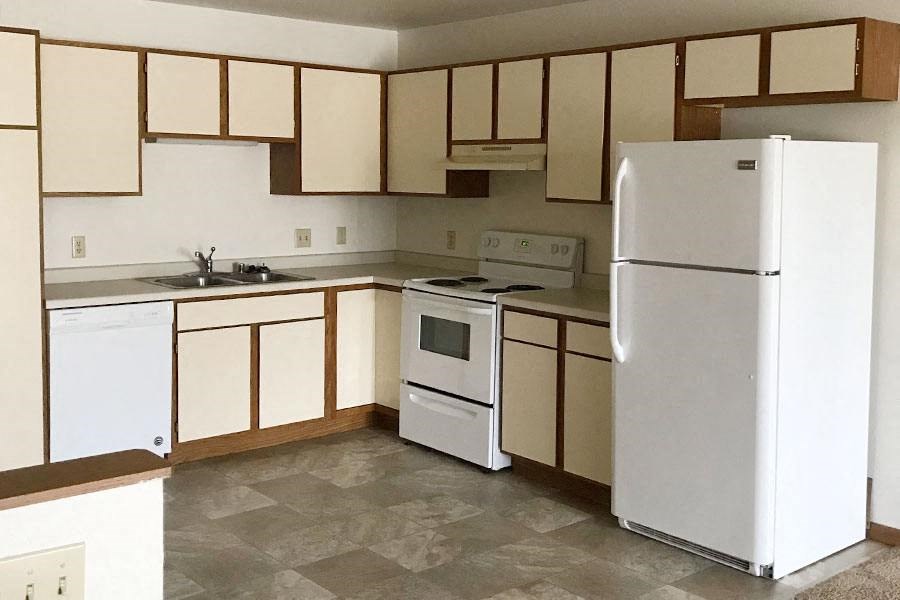 an empty kitchen with a refrigerator and a sink