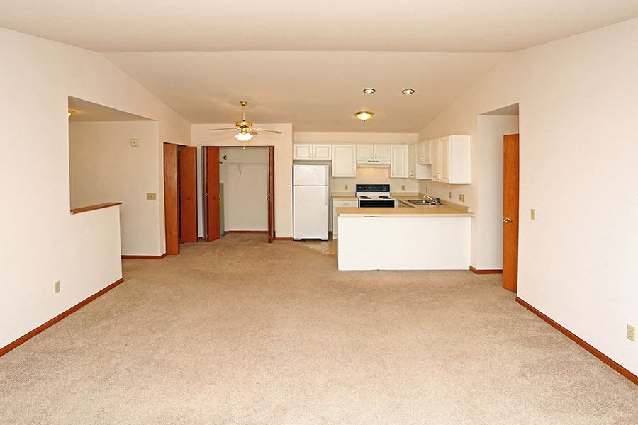 an empty room with a kitchen and a living room
