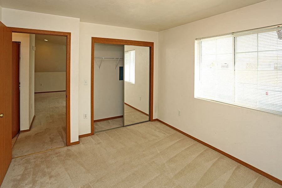 an empty living room with a large window and a mirror