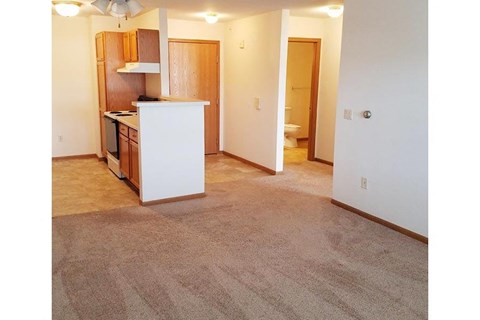 an empty room with a kitchen and a living room