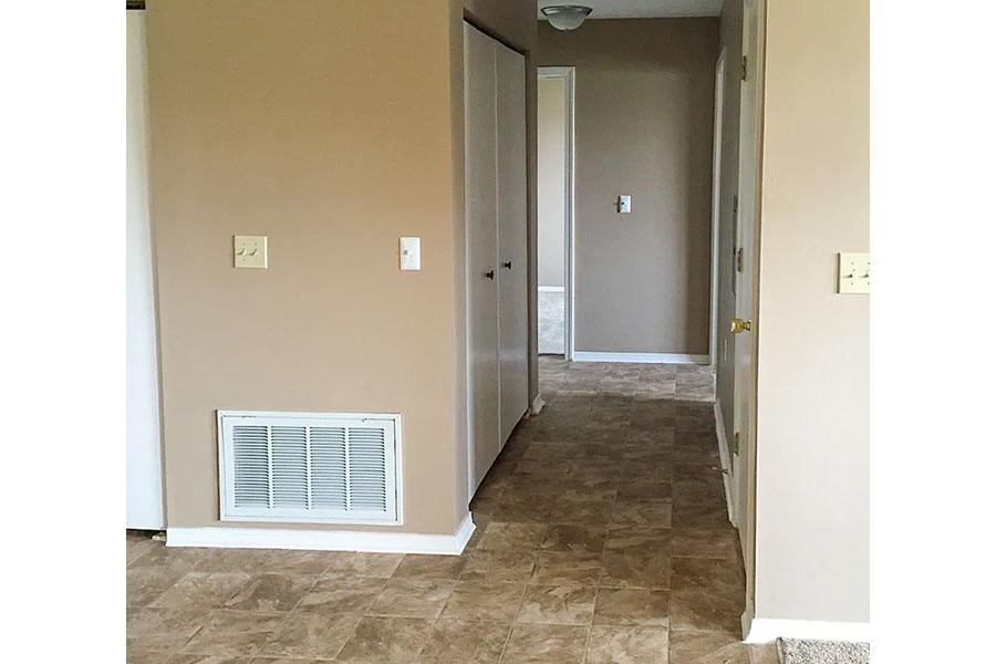 A hallway with a tiled floor and a wall-mounted air conditioner unit.