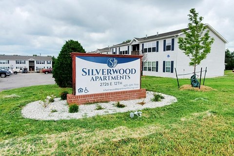 A sign for Silverwood Apartments is in front of a building.