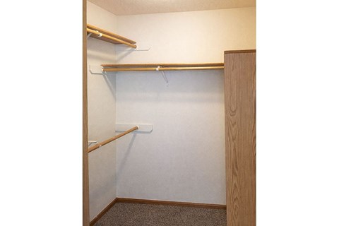 A small closet with a white door and a brown shelf.