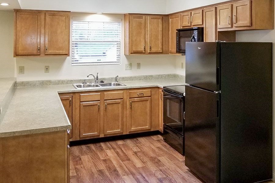 A kitchen with wooden cabinets and a black refrigerator.